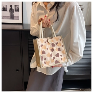 Detail of canvas bento bag with heart pattern and woven rope handle held by model