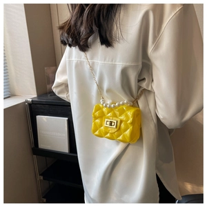 Detail of yellow quilted jelly bag featuring pearl handle and gold chain strap