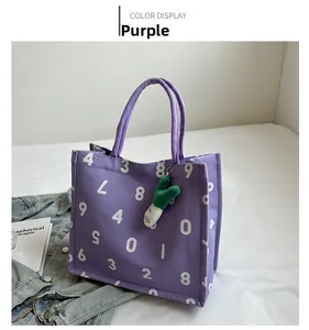 Close-up of purple canvas tote bag with white number print and green plush charm