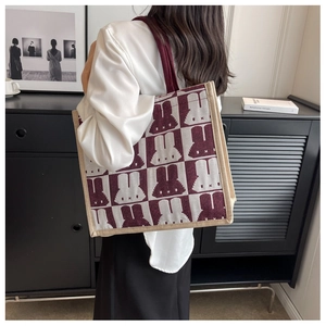 Macro detail of checkered tote bag fabric featuring burgundy cartoon rabbit prints