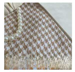 Close-up of beige houndstooth tote bag featuring elegant white pearl bead handle detail