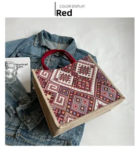 Detailed macro of ethnic geometric weaving and red handles on a large tote bag