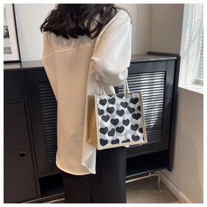 Rear view of a model carrying a small tote bag with black and white heart patterns