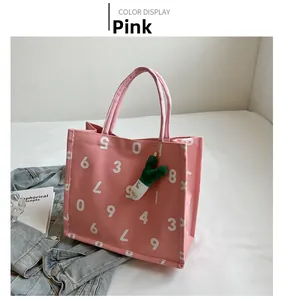 Pink canvas tote bag detail featuring white letter print and cute green plush charm