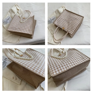 Detail of houndstooth tote bag featuring elegant pearl handle and wooden button closure