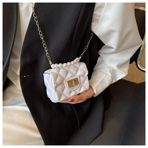 Close-up of white quilted mini crossbody bag with pearl handle and gold chain strap