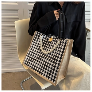 Detail of houndstooth tote bag featuring pearl chain strap and linen fabric texture