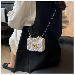 Detail of white quilted mini bag featuring pearl handle and gold chain strap close-up