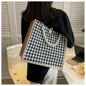 Detail of houndstooth tote bag featuring pearl bead handle and wooden button decoration