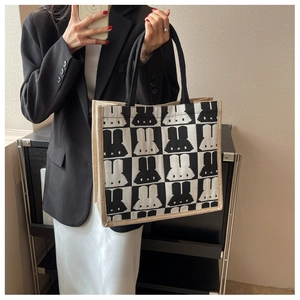 Detailed view of checkered tote bag with pixel rabbit pattern and beige woven texture
