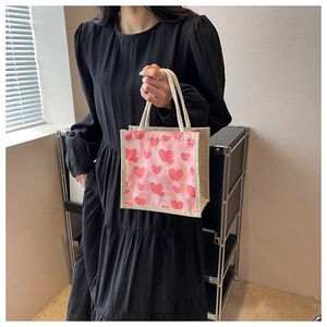 Close-up of heart print linen lunch tote with sturdy white rope handles on black dress