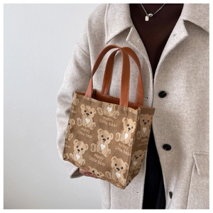 Close-up of bear jacquard canvas tote with brown leather handles on autumn coat
