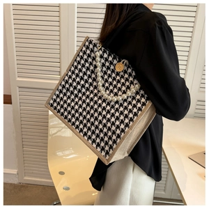 Detailed close-up of houndstooth tote bag featuring pearl handle and wooden button decoration