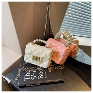 Close-up of quilted mini jelly bag with pearl handle and golden chain strap detail