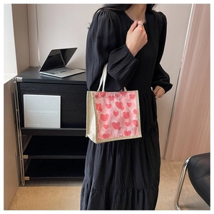 Close-up of heart pattern canvas lunch bag with round rope handles on black dress