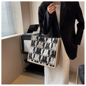 Close-up of black and white checkerboard tote bag with rabbit print and woven handles