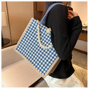 Detail of blue and white tweed tote bag with pearl chain and wooden button accents