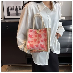 Detail of linen tote bag featuring red heart patterns and a round wooden button closure