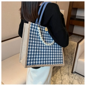 Close-up of blue houndstooth tote bag featuring pearl chain and wooden button details