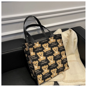 Detail of black canvas tote bag featuring yellow cartoon bears on a leather sofa