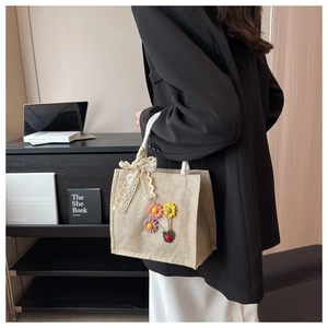 Detailed view of linen tote with floral embroidery and white lace bow decoration