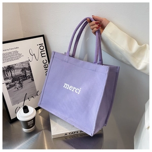 Macro shot of durable purple canvas texture and white merci text print on a tote bag