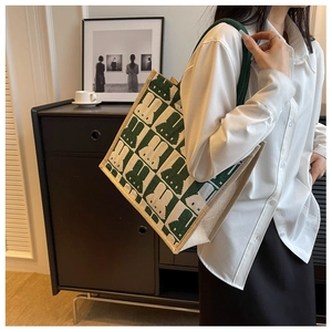 Detail of a green rabbit print tote bag showing the textured canvas and long shoulder straps