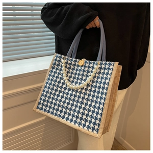 Detail of houndstooth tote bag with pearl handle and wooden button closure