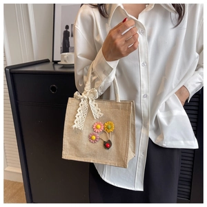 Detailed close-up of a linen handbag with handmade crochet flowers and white lace bow
