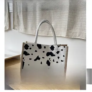 Detail view of the cow print pattern on a sturdy canvas tote bag with beige handles