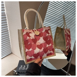 Detail of canvas tote bag with red heart patterns and rustic hemp rope handles