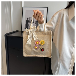 Linen handbag detail with floral decor, ladybug accent, and white lace bow