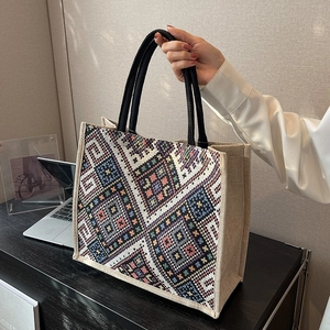 Ethnic geometric jute tote bag with black handles in a modern office setting