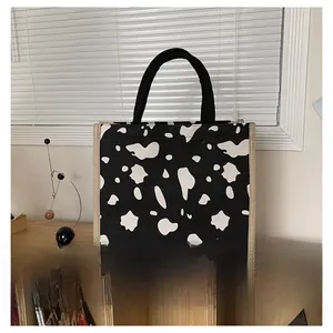 Detail of cow print linen tote bag featuring black woven handles and natural jute piping