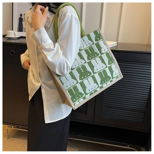 Close-up of the green rabbit pattern tote bag with woven rope handles worn by a model