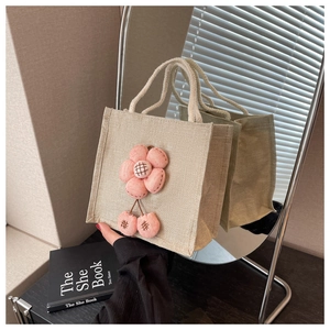 Detail der Leinen-Lunchtasche mit rosa 3D-Blume und Kirsch-Anhängern in Spiegelreflexion
