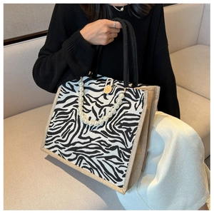 Detail of zebra print tote bag with woven handles, pearl chain and wooden button closure