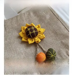 Detail of handmade sunflower charm with knitted decorative balls on a burlap bag