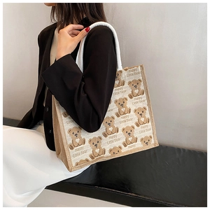Detail of large canvas tote bag with cartoon bear print and woven handle on model
