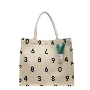 Large beige canvas tote bag with black number print and green plush onion charm accessory