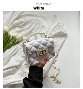 Detail of white quilted mini jelly bag with pearl handle and golden chain strap