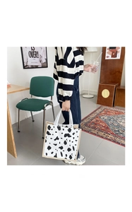 Detailed close-up of the cow print tote bag featuring canvas texture and beige piping trim