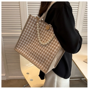 Detail of canvas tote bag with houndstooth pattern, pearl chain, and wooden button accent