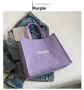 Detail of purple canvas tote bag with white merci text and stylish rope handle design