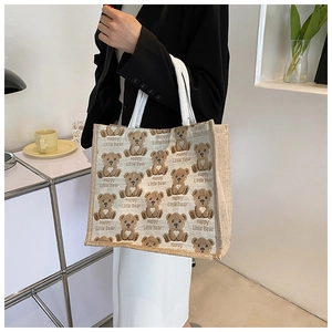 Detail of beige canvas tote bag with brown bear print and white rope handles