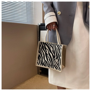 Dettaglio di borsa in juta con stampa zebrata e manici in fibra naturale per look casual