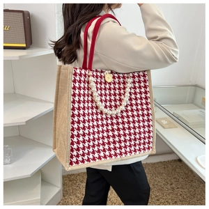 Detail view of red houndstooth tote bag featuring pearl strap and jute canvas texture