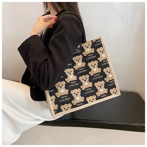 On-shoulder view of the canvas tote bag featuring black fabric and cartoon bear patterns