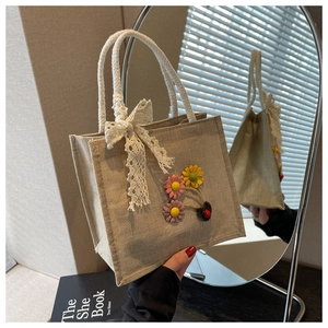 Close-up of linen tote bag with white rope handles and decorative floral lace bow