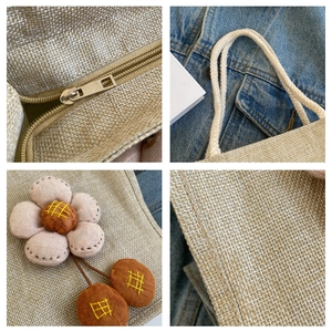 Detail der Leinen-Lunchtasche mit Plüschblume und hochwertigem Metallreißverschluss